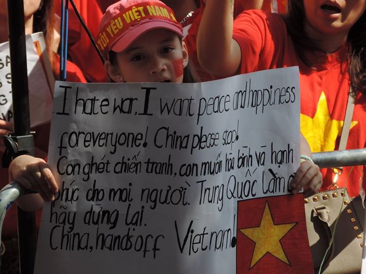 Một em bé mang hia dòng máu Anh - Việt mang biểu ngữ phản đối